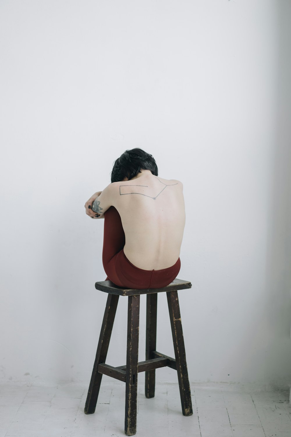 topless woman sitting on chair near white wall