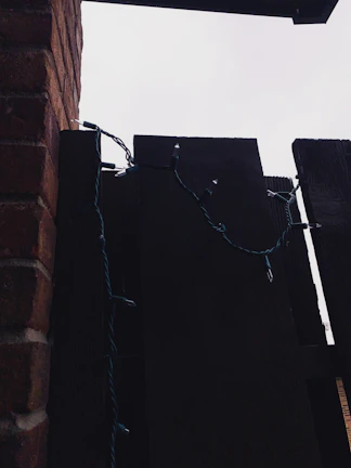 Battery-operated string lights draped casually over a rustic wooden fence at dusk.