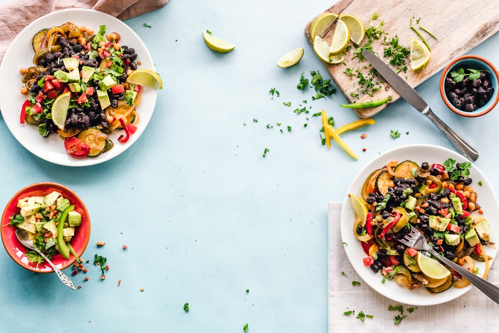 three bowls of salad dish with lemon on table