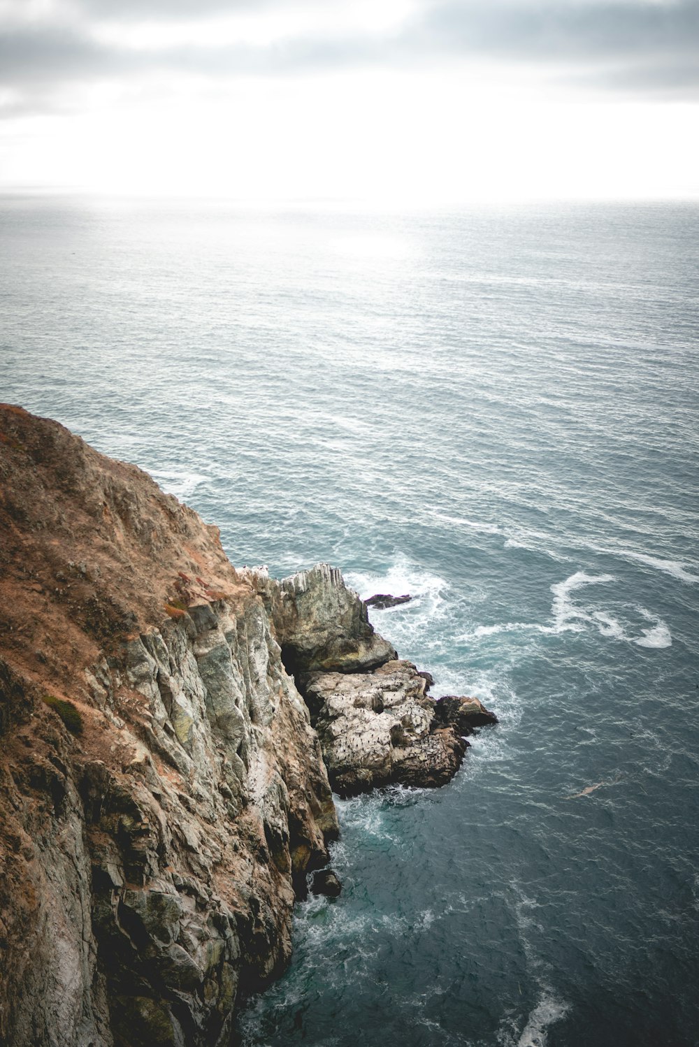 brown rock formation beside body of water