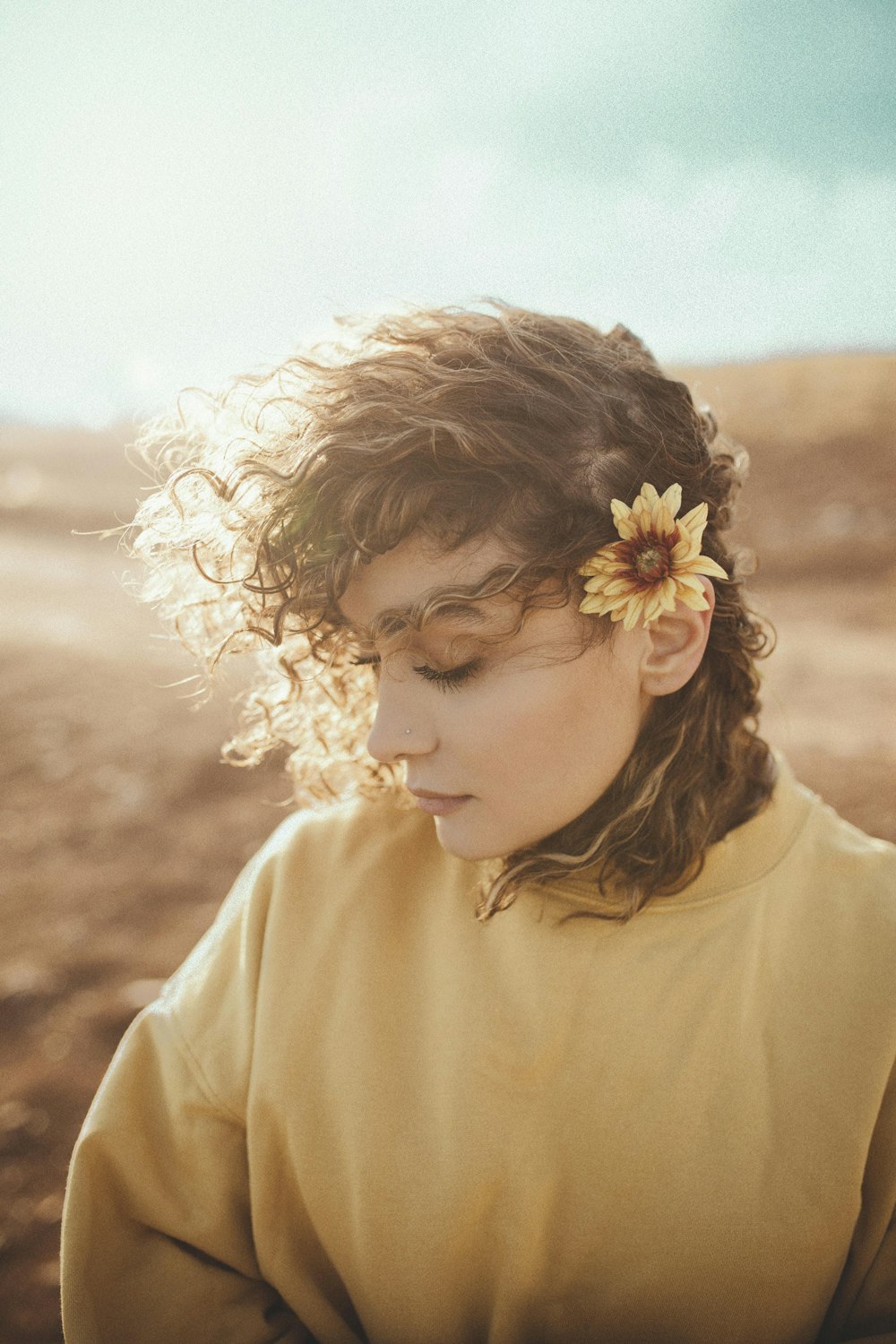 woman wearing yellow sweat shirt with flower on right ear