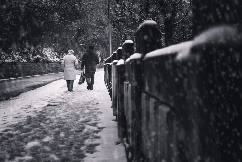 deux personnes marchant sur le trottoir à la neige