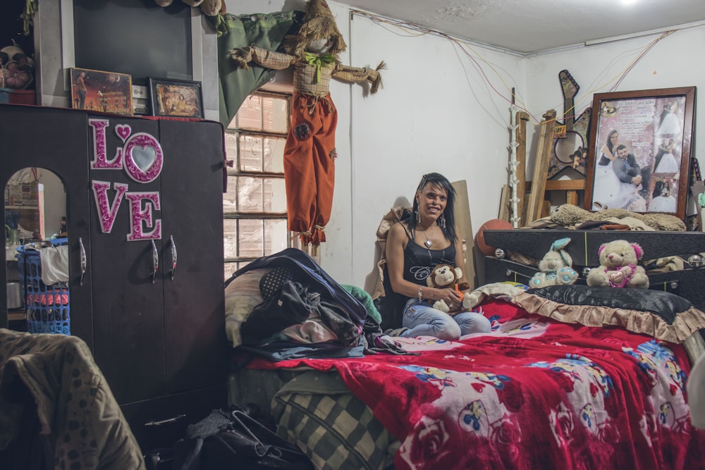 Mujer vestida con camisa negra de tirantes finos sentada sobre colcha roja