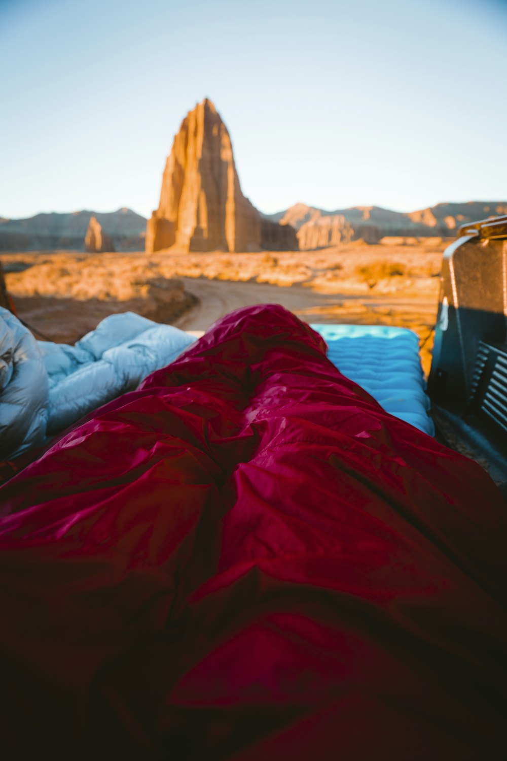 person in sleeping bag overlooking rock formations