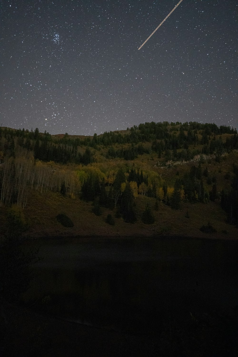 shooting star over green mountain during nighttime