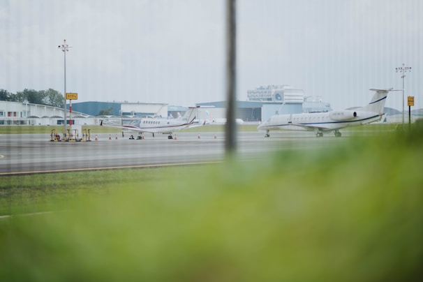 Aerial shot of multiple private jets lined up at a modern airport hangar.