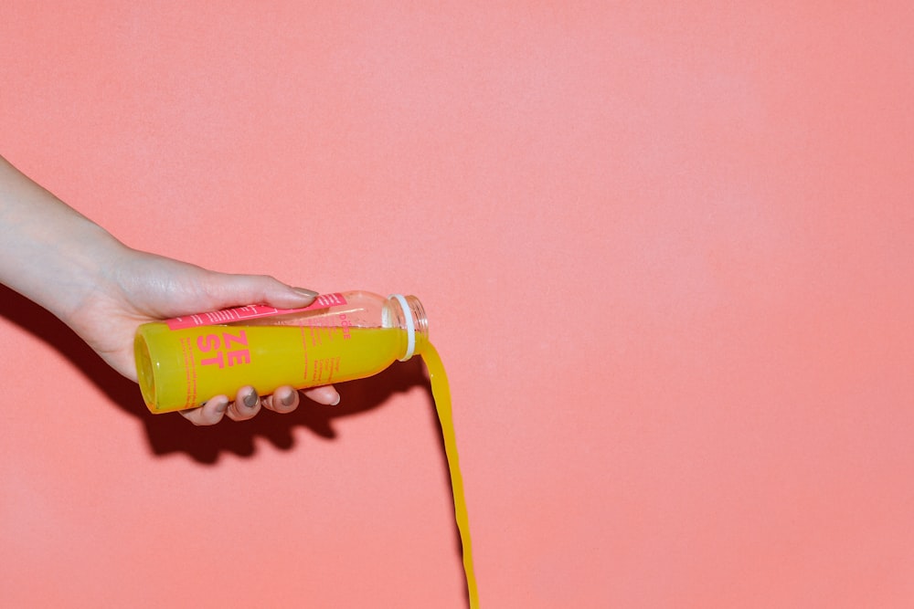 person pouring bottle of yellow liquid