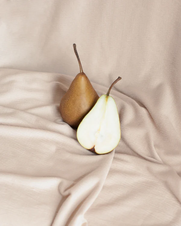 Poires mûres aux reflets dorés en gros plan — la tête poire William royale d'English Pear & Freesia de Jo Malone London, par la parfumerie Olara