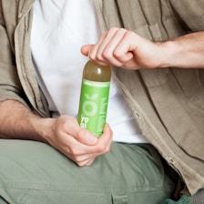 person holding green labeled bottle