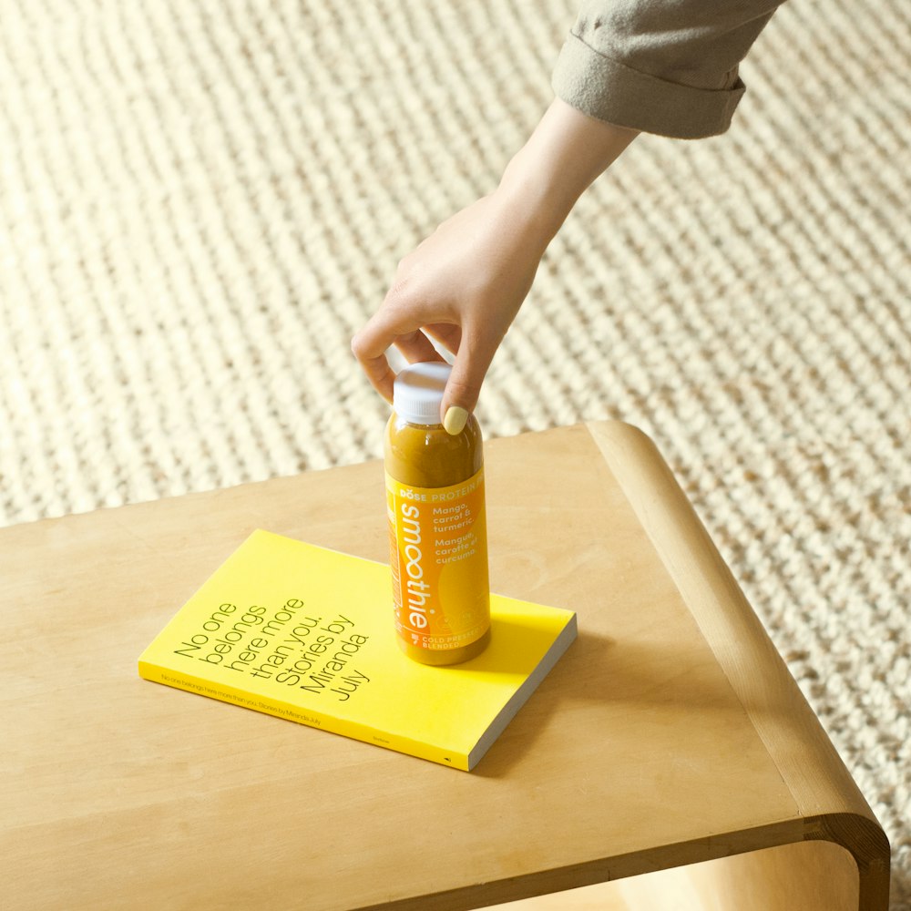 person holding yellow plastic bottle