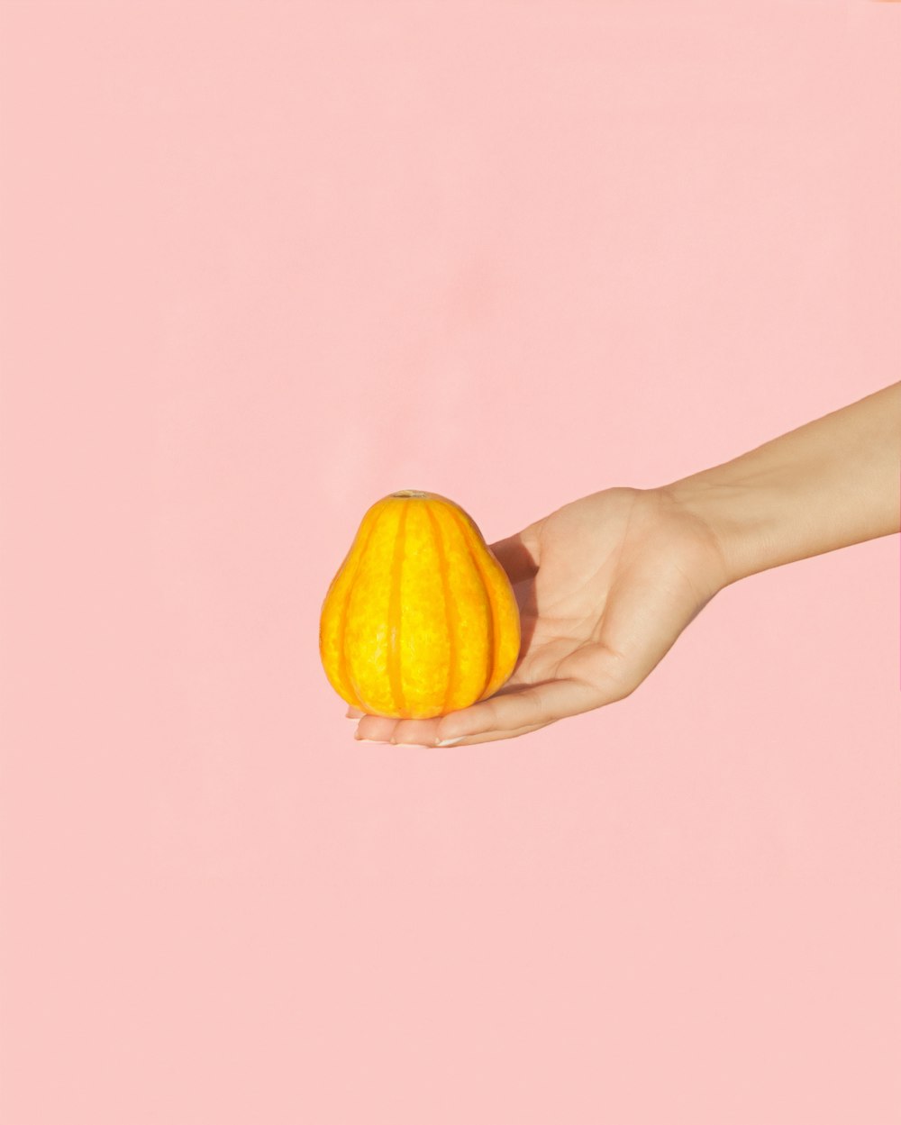 人の手のひらに洋ナシの形をした黄色い果実