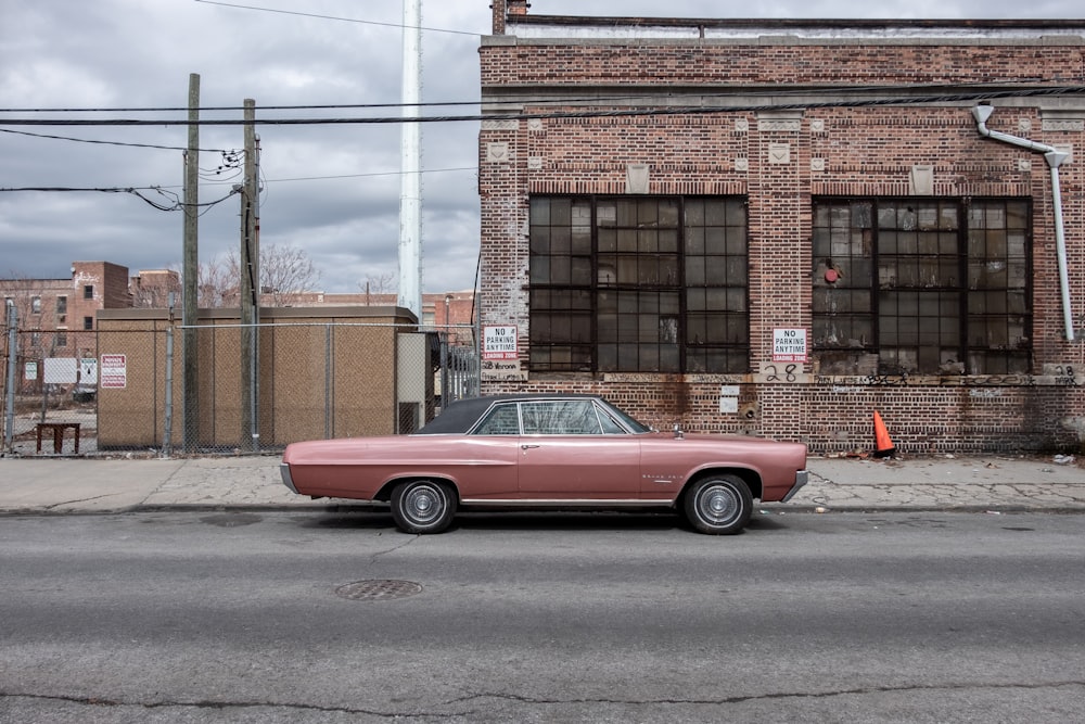 parked red coupe beside house