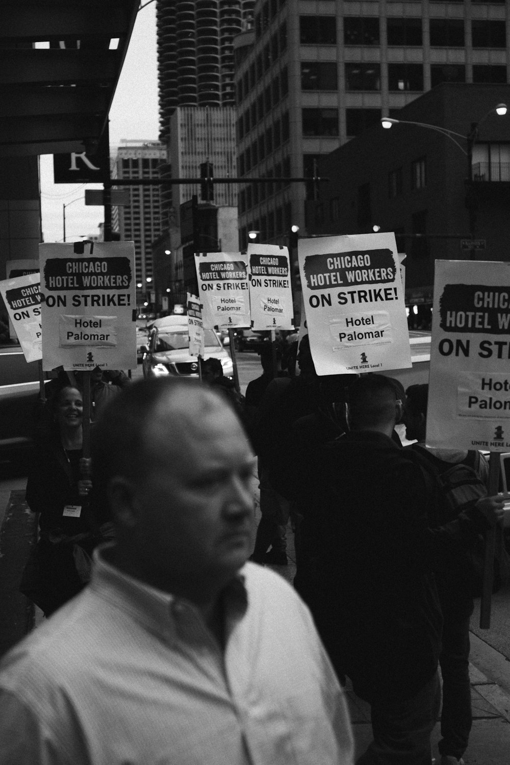 greyscale photo of man wearing dress shirt near signage