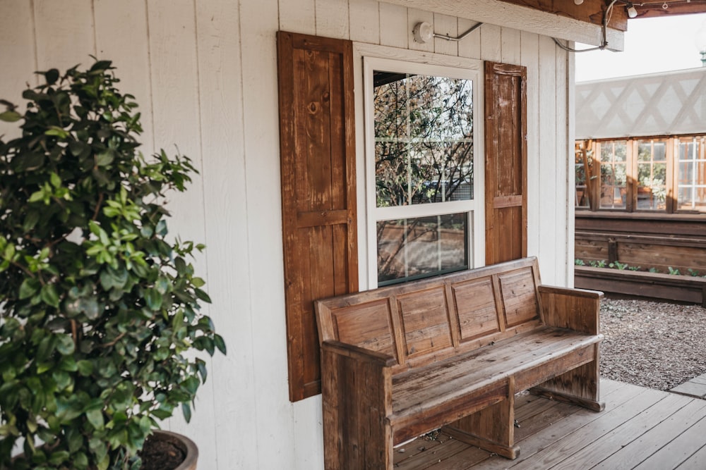 brown wooden bench beside white wooden wall