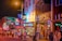A lively street scene at night, featuring brightly lit neon signs and bustling crowds in front of B.B. King's Company Store. The buildings are adorned with colorful signage and the atmosphere is vibrant with a sense of nightlife excitement.
