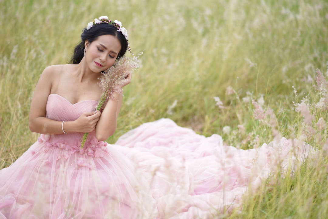 woman holding bouquet of flowers sitting on green field