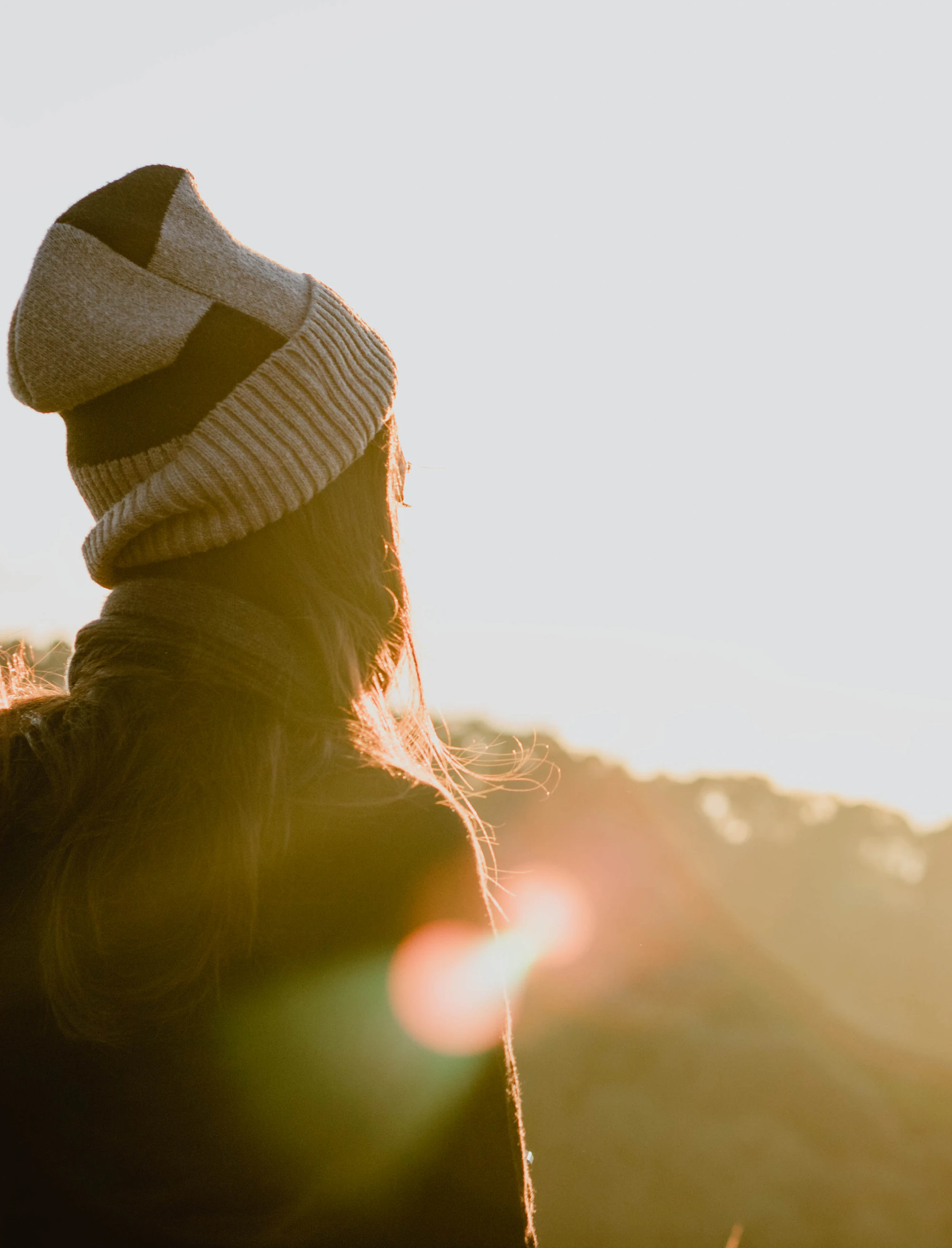Woman standing on a mountain ridge at sunrise, looking out over the valley below