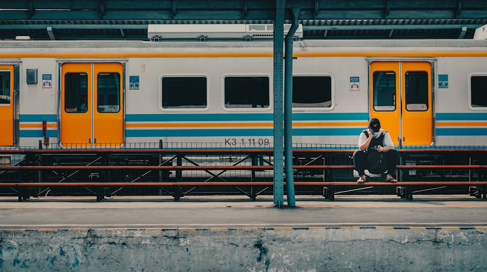 person sitting on bench near train