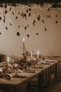 A softly glowing farmhouse chandelier hanging above a rustic wooden dining table set for family dinner.