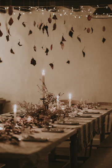 A softly glowing farmhouse chandelier hanging above a rustic wooden dining table set for family dinner.