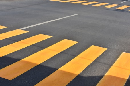 Close-up of bright yellow thermoplastic road markings freshly applied on a busy Mumbai street.