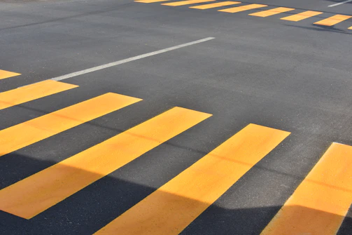 Close-up of freshly painted pedestrian crossing stripes on asphalt under bright sunlight.