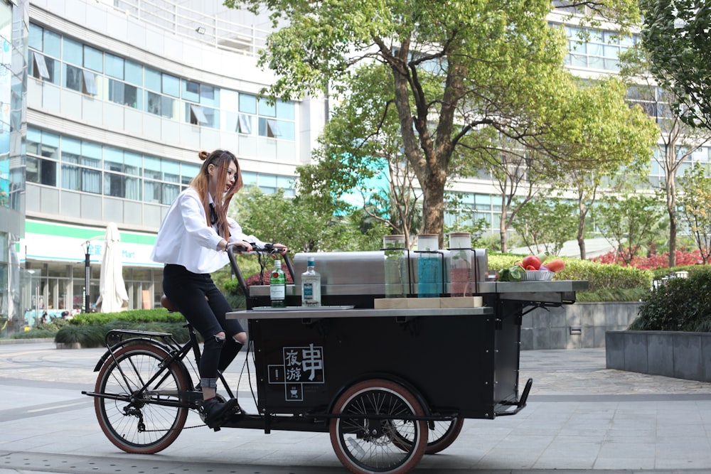 woman riding on black food cart near concrete building