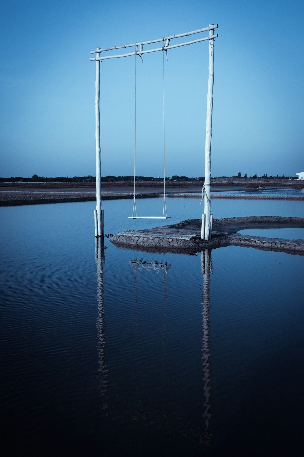 white metal swing surrounded of water during daytime