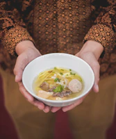 Hands preparing siomay with smooth, translucent skins in a bright kitchen.