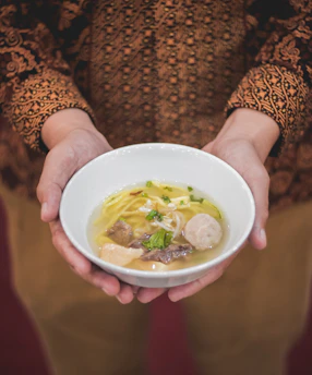 Hands preparing siomay with smooth, translucent skins in a bright kitchen.