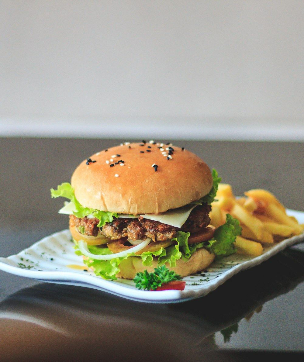 hamburger with lettuce and fries on white ceramic plate