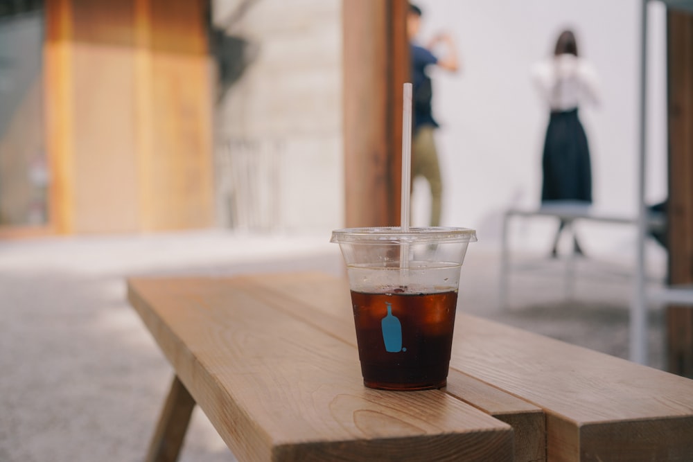 clear plastic cup half empty on wooden bench