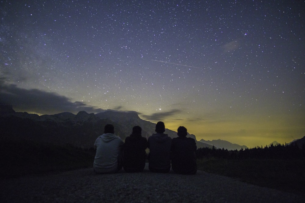 four people sitting while watching sunset