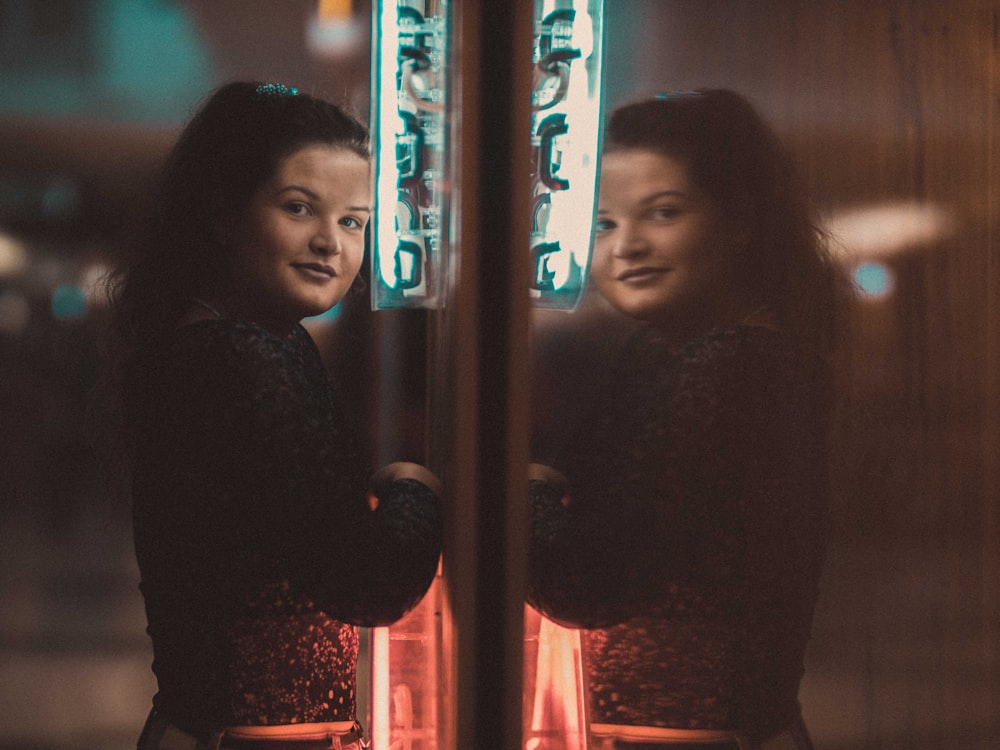 standing woman facing in front of illuminated signage at night time