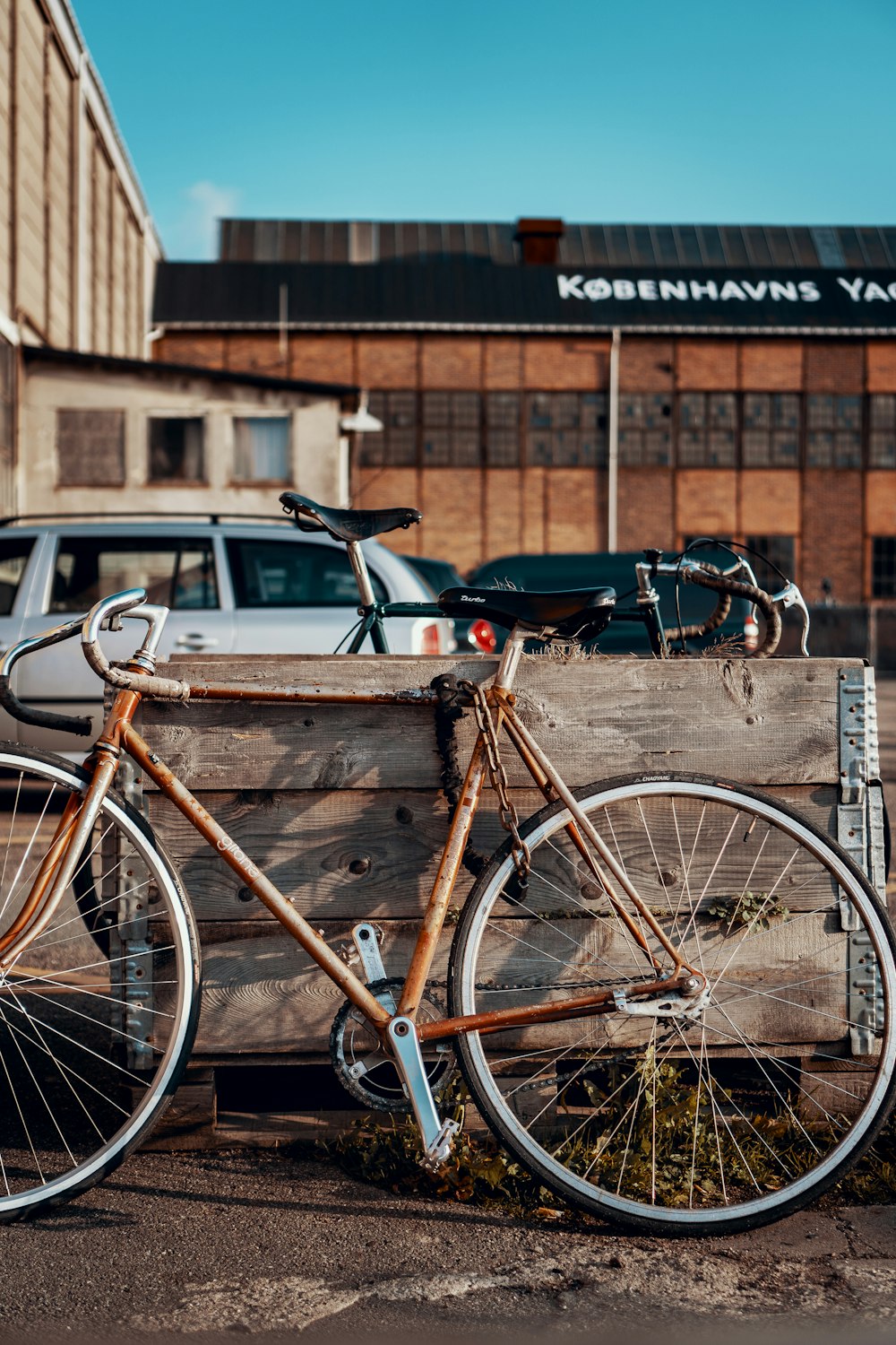 bicicleta marrom estacionada ao lado do painel de madeira durante o dia
