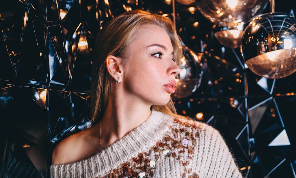 woman in gray sweater standing near glass panels