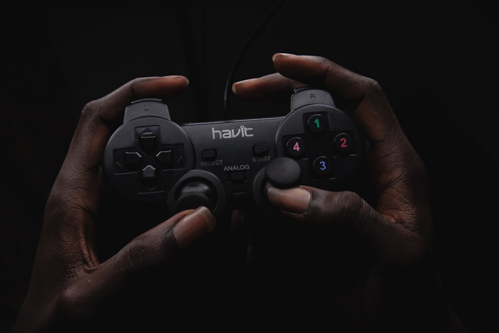 personne tenant une manette de jeu Havit noire