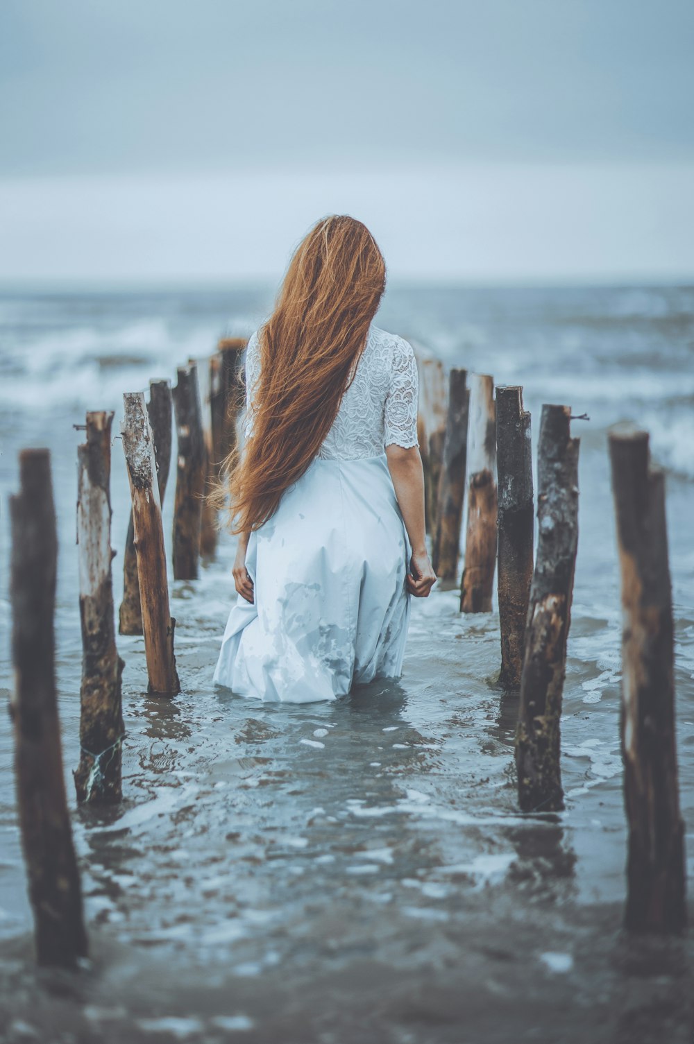 woman standing on water in between logs