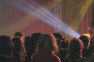 Audience members immersed in the music, eyes closed and faces glowing under soft stage lights.