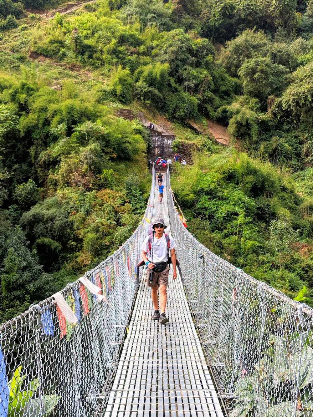 man walking on gray metal hanging bridge during day