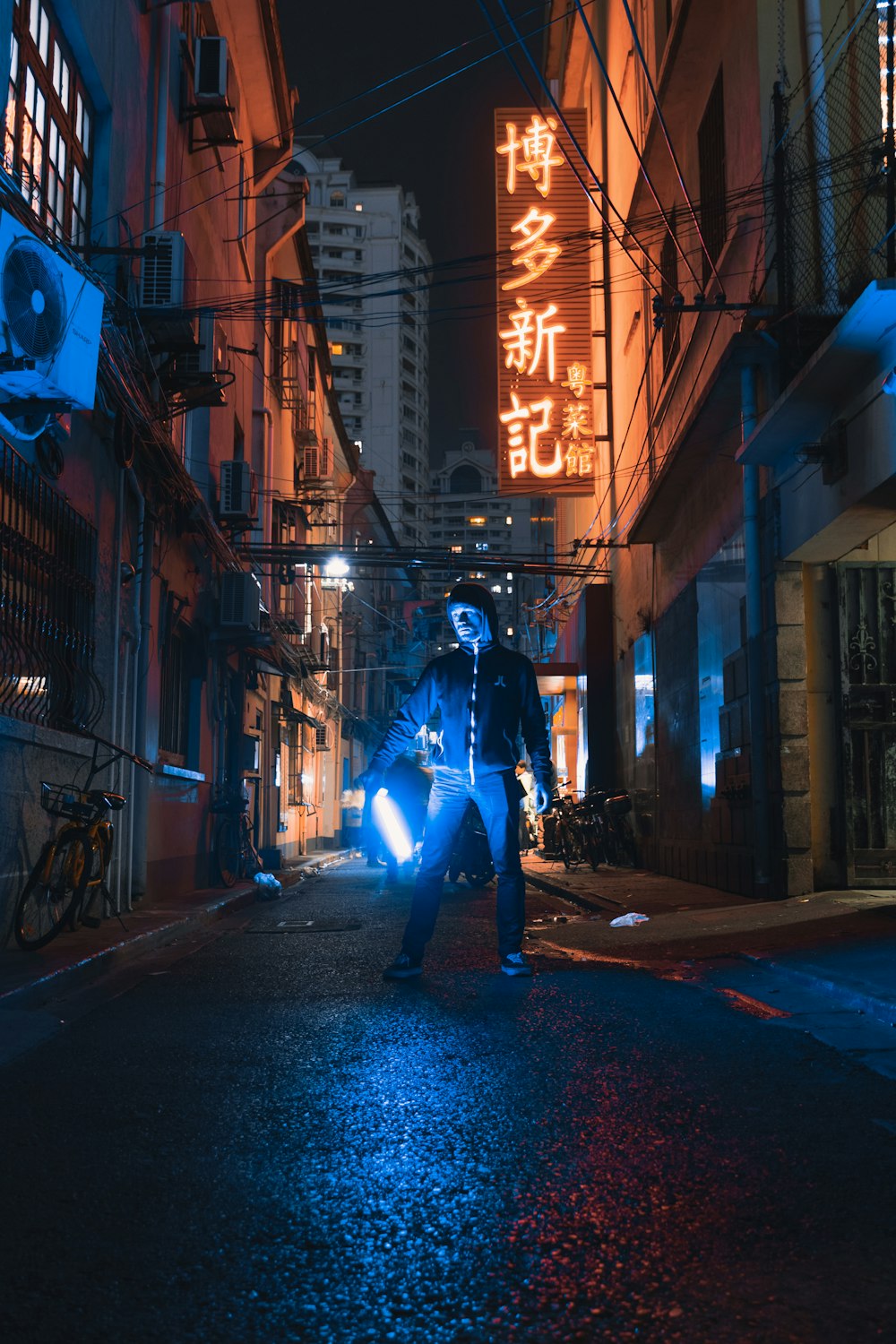 Persona de pie y sosteniendo luz entre edificios de concreto durante la noche