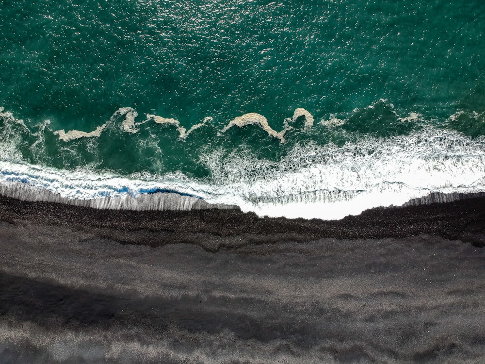 fotografia aerea delle onde che si infrangono sulla scogliera durante il giorno