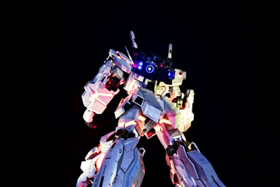 A striking robot head glowing with neon blue and pink lights against a dark background.
