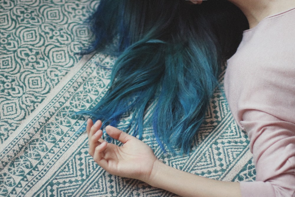 mulher com cabelo azul deitado no tecido branco e verde