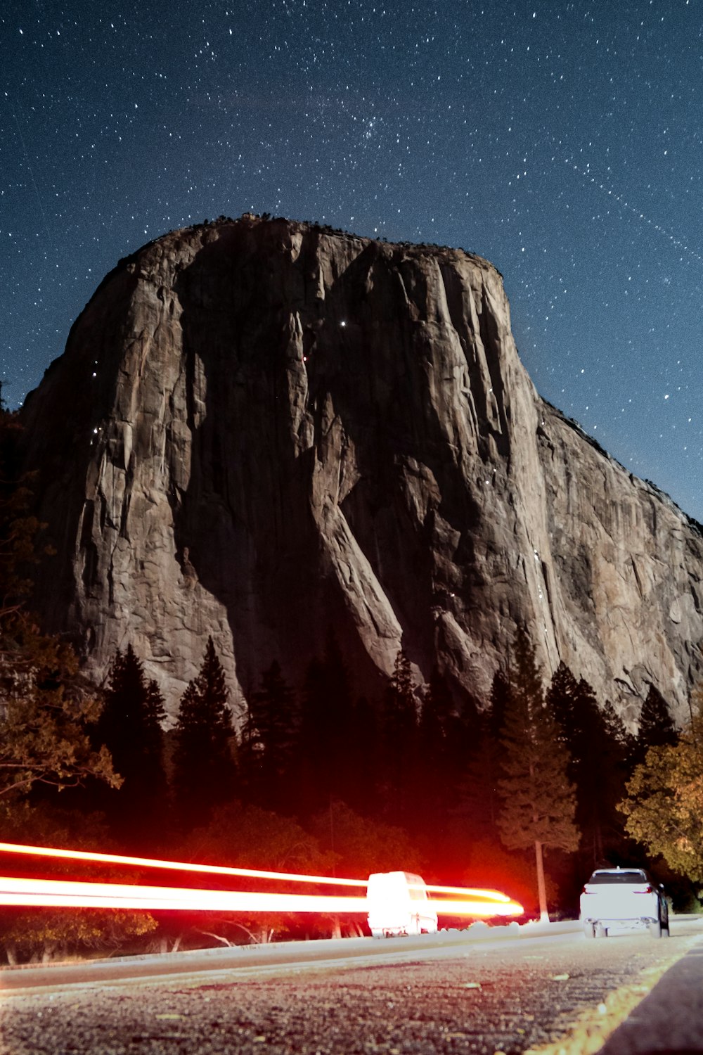 light streak photography of vehicle in the middle of the street near rocky mountain