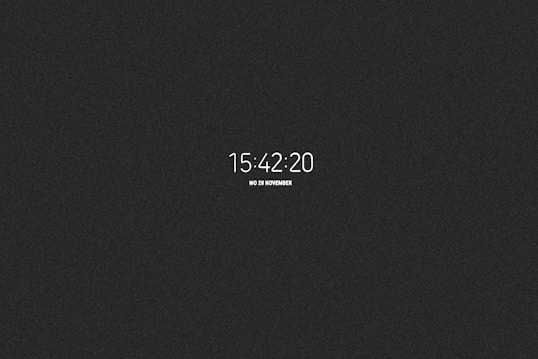 A digital clock display shows the time 15:42:20 with a date reference of Wednesday, 28 November. The background is a plain black color, which highlights the white alphanumeric characters used for the time and date.