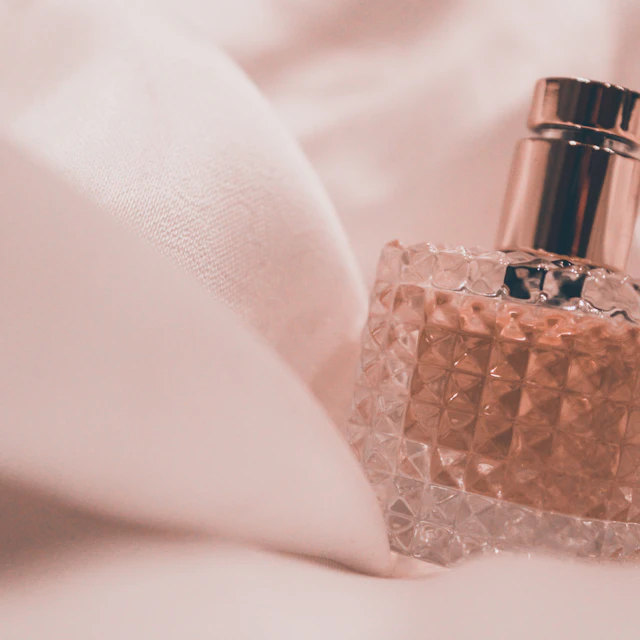 A glass perfume bottle on a table in soft light