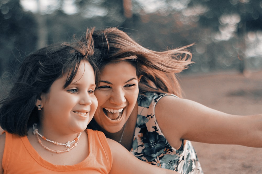 woman beside girl on brown field