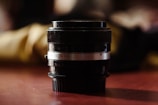 Close-up of a vintage camera lens with soft cream highlights on matte black background.