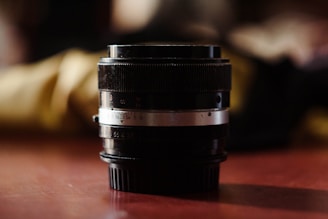 A high-quality camera lens sitting on a vintage camera body with a blurred studio background.